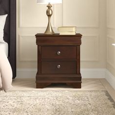 a nightstand with a lamp on top of it next to a night stand and bed