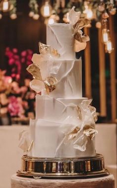 a three tiered white wedding cake with gold accents