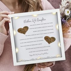 a woman holding up a card with two hearts on it and lights in the background