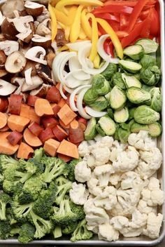 a tray filled with vegetables including broccoli, cauliflower, peppers and mushrooms