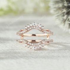 a rose gold ring with diamonds on the top and bottom, sitting on a white surface