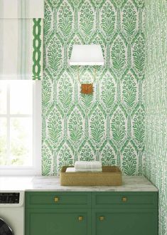 green and white wallpaper in the corner of a room with a lamp above it