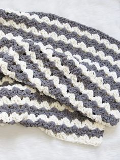 two crocheted afghans laying on top of each other in grey and white