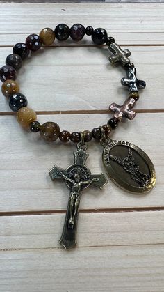 Beautiful Rosary Bracelet in bronze with 8mm Jade Beads and 4mm semi precious, Tiger Eye round beads, we mark the 3 Hail Marys with three metal crosses, use Beadnova Crystal Strong String, the charms of the bracelet are of Saint Michael the Archangel on the front and on the back it says "Pray for us" and the cross on it is of the cross of Saint Benedict". 1" measure or 2 cm . The measurement of the Bracelet is 7" or 17.8 cm. Beautiful instrument of prayer or to give as a gift on any occasion. De Spiritual Beaded Rosary Bracelet With Crucifix, Spiritual Rosary Bracelet With Miraculous Medal, Spiritual Bracelets With Miraculous Medal As Gift, Spiritual Beaded Bracelets With Miraculous Medal, Spiritual Cross Bracelets, Adjustable Spiritual Rosary For Healing, Spiritual Rosary Bracelet With Round Beads As Gift, Spiritual Rosary Bracelet With Round Beads For Meditation, Adjustable Crucifix Spiritual Bracelet