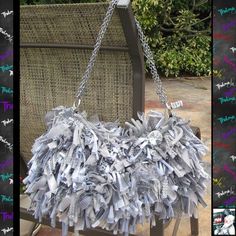 a bag made out of newspaper sitting on top of a wooden chair with chains hanging from it