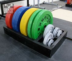 a row of different colored barbells sitting on top of each other in a gym