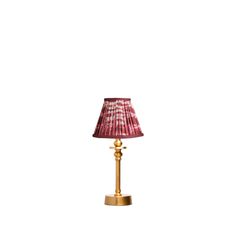 a lamp with a pink shade on it and a gold base is shown against a white background