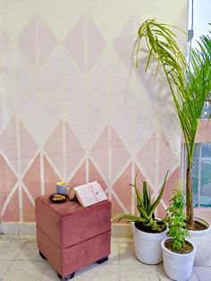 three potted plants are sitting in front of a pink wall with geometric designs on it