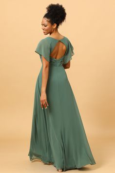 a woman in a long green dress is smiling and looking at the back of her dress