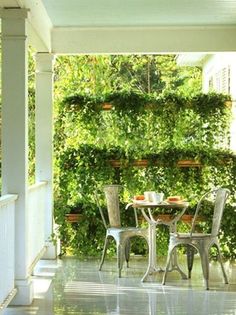 an outdoor table and chairs on a porch with ivy growing up the wall behind it