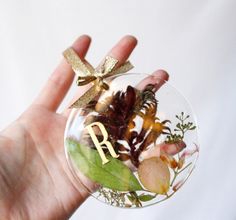 a hand holding a glass ornament with flowers and leaves