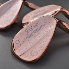 two rose gold colored golf club head covers with the words titleist engraved on them