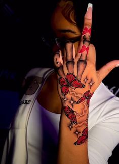 a woman is holding her hand up to show the butterfly tattoos on her left arm