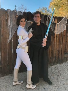 a man and woman dressed up as star wars characters posing for a photo in front of a fence