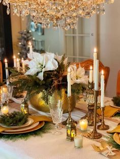 a dining room table is set with candles, plates and napkins for christmas dinner