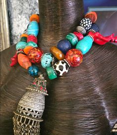 Here's a wild and exotic, OOAK Artisan Tribal Statement Necklace - Statement Pendant for those of you who like your accessories untamed! Adjusting from 16-19", this piece features a vintage metal tassel pendant with dangles, Krobo, magnesite, resin, agate, wood, zebu bone*, branch coral, chrysocolla, and assorted metals. A bold, chunky and heavy piece, this closes with a fancy silver tone tribal hook and a 3" silver tone extender chain. The pendant measures 5" x 2" and has inlaid glass. A perfec Traditional One-of-a-kind Multicolor Beaded Necklace, Artisan Tassel Necklaces For Festivals, Bohemian Turquoise Beaded Necklaces For Festive Occasions, Bohemian Style Turquoise Beaded Necklace For Festive Occasions, Traditional Multicolor Tassel Jewelry, Eclectic Multicolor Beaded Necklace For Festivals, Bohemian Beaded Necklaces With Large Beads For Festive Occasions, Bohemian Jewelry With Large Beads For Rituals, Bohemian Festive Beaded Necklace With Large Beads