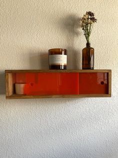 two vases with flowers are sitting on a shelf