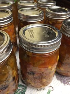 many jars filled with food sitting on top of a table next to a cloth covered tablecloth