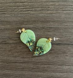 Mint green leaf earrings with holo-flakes and gold foil.  These mint green dangly earrings are sure to help you have a fresh start to the day. These earrings have gold colored stainless steel posts.  **DISCLAIMER** Please note, each pair of earrings is unique.  There may be small flaws, like air bubbles, rogue dog hairs, etc.  If you're looking for perfection, this pair may not be for you.  But if you're looking for something fun and unique, buy away! Green Leaf-shaped Earrings For Pierced Ears, Green Leaf-shaped Earrings For Gift, Green Leaf-shaped Earrings As A Gift, Green Leaf-shaped Earrings, Green Leaf-shaped Jewelry With Matching Earrings, Handmade Green Leaf-shaped Earrings, Green Resin Drop Earrings, Nature-inspired Green Teardrop Earrings, Nickel-free Green Resin Earrings