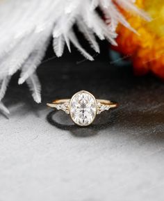 a close up of a ring on a table with flowers in the background and feathers