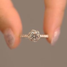 a woman's hand holding a ring with a diamond in the middle and on top