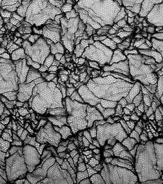 black and white photograph of rocks with cracks in the rock face, taken from above