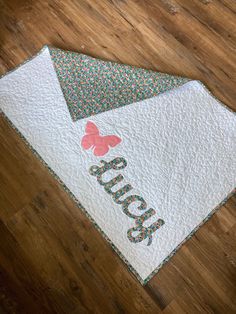 a close up of a quilt on a wooden floor with the name sue written on it