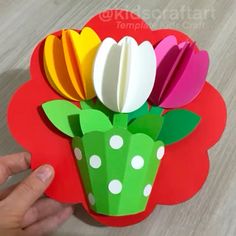 a person is holding up a paper flower