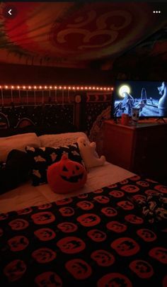 a bedroom decorated for halloween with pumpkins on the bed and a tv in the corner