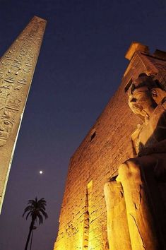 an obelisk and statue in front of the egyptian temple at night