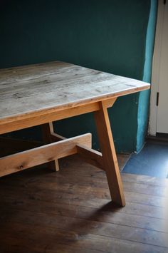 a wooden table sitting on top of a hard wood floor next to a green wall