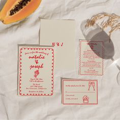 the wedding stationery is laid out on top of the table with fruit and paper