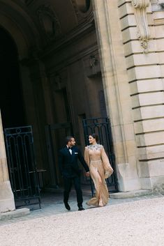 a man and woman in formal wear walking out of an entrance to a large building