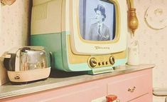 an old tv sitting on top of a pink dresser