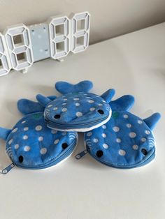 two blue and white stuffed animals sitting on top of a table next to a clock