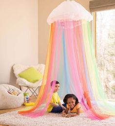 two children laying on the floor in front of a colorful canopy