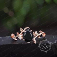 a black diamond ring sitting on top of a piece of wood with leaves around it