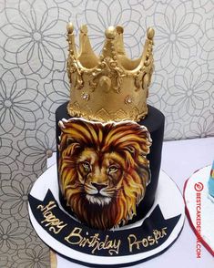 a birthday cake with a lion on top and a crown on the side, sitting on a table