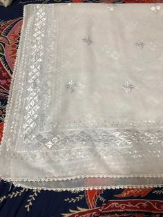 a white table cloth with silver sequins on it sitting on top of a blue and red blanket