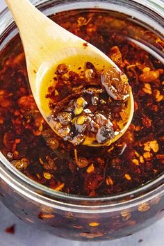 a wooden spoon filled with chili sauce on top of a table