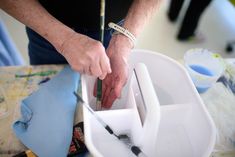 an older man is measuring something in a container with a tape around his wrist and holding a pair of scissors