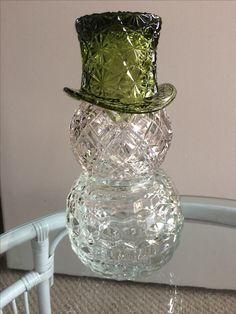 a glass snowman sitting on top of a table next to a white wicker chair