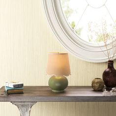 a table with two vases and a lamp on it next to a round window