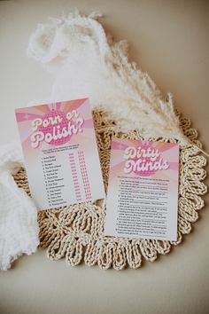 two pink flyers sitting on top of a doily next to a white cloth and some yarn