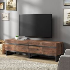 a flat screen tv sitting on top of a wooden cabinet in front of a gray wall