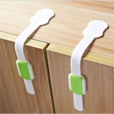 two white handles on wooden cabinets with green clips attached to the doors and drawer knobs