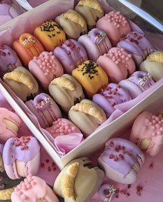 a box filled with lots of different colored pastries on top of a table next to each other