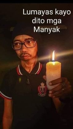 a man holding a lit candle in his right hand with the caption lumayas kayo dito nga manayak