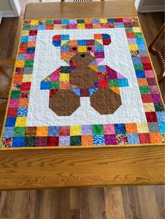 a teddy bear quilted on top of a wooden table