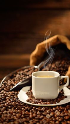 a cup of coffee sitting on top of a pile of coffee beans